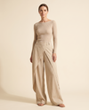 Top beige con scollo a barca e pantaloni a gamba larga sovrapposti.